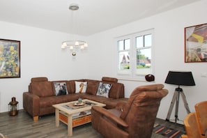 A living room with a brown leather sofa, a wooden coffee table, and a lamp. - Vacation Home in Milan - Waterfront vacation home with a fireplace, ocean view, and garden - (Gager)