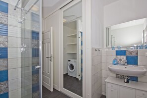 A modern bathroom with a glass shower enclosure, a built-in washing machine, and a sink with a mirror. - Vacation home Milan - waterfront vacation home with fireplace, sea view and garden - (Gager)