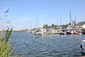 A marina with multiple boats docked, calm water, and a clear sky.