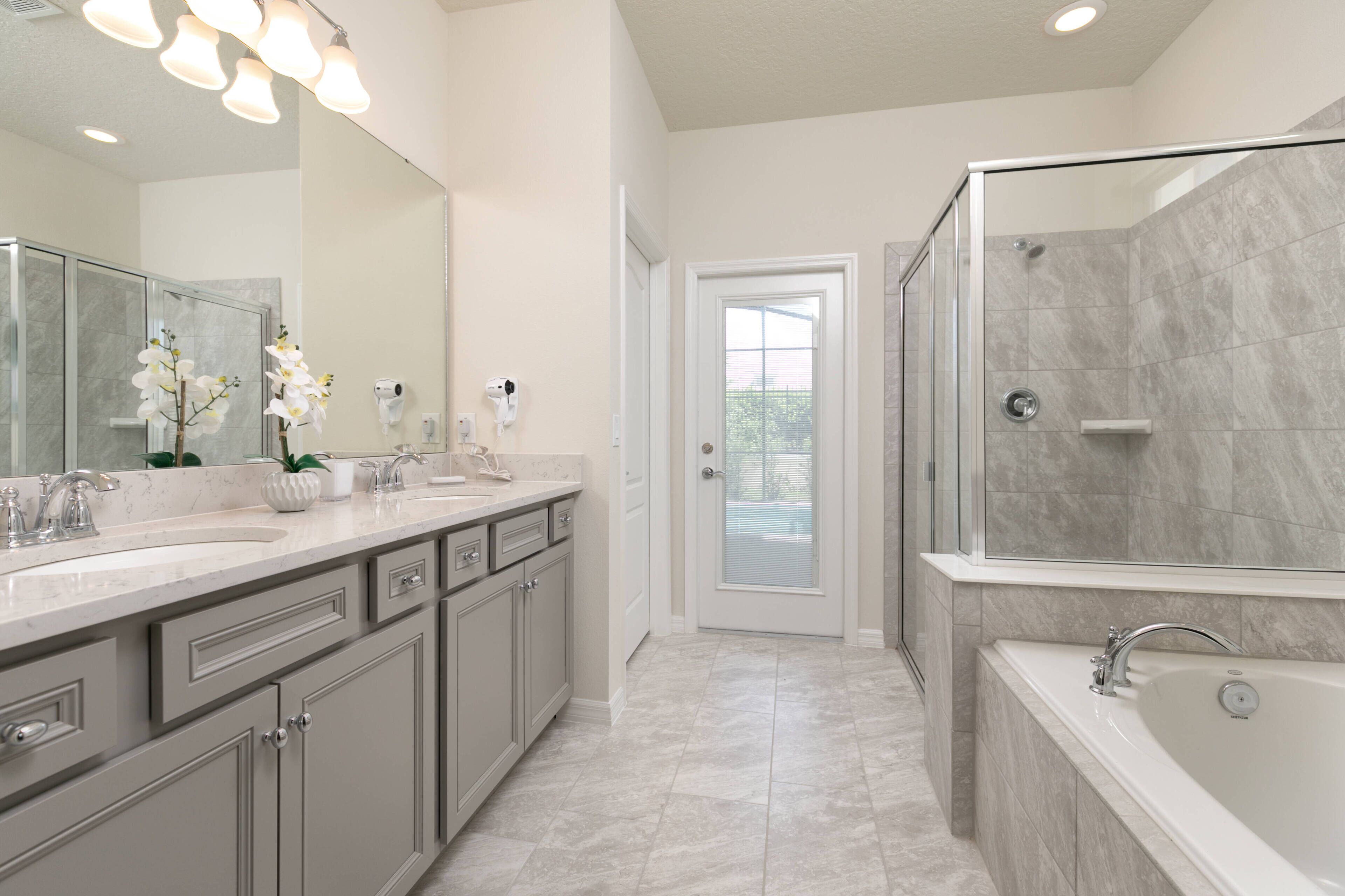A modern bathroom with a large mirror, two sinks, a shower, and a bathtub.