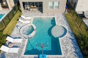 An outdoor swimming pool with lounge chairs, a hot tub, and a basketball hoop. - Family Escape With Private Pool & Themed Rooms (Kissimmee)