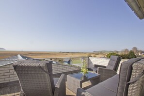 Eine Terrasse mit Korbmöbeln und Blick auf eine flache Landschaft.