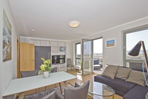 Ein modernes Wohnzimmer mit Essbereich, einer Couch und einem Balkon mit Blick.
