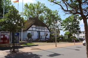 A traditional half-timbered house with a thatched roof, situated on a paved street with bicycles parked in front. - Patio, free use of the AHOI adventure pool and sauna - Villa Antje FeWo 04 - (Göhren)