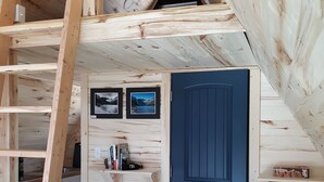 Un dormitorio tipo loft de madera con puerta azul, estanterías de madera y una escalera.