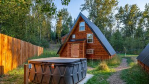 Una cabaña de madera con un jacuzzi y un camino que lleva a él.