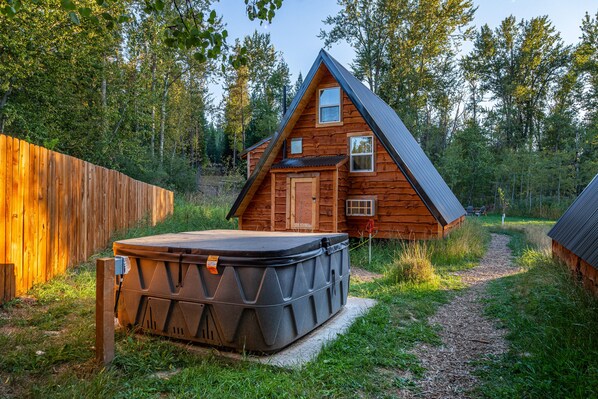 Une cabane en bois avec un jacuzzi et un sentier menant à celle-ci.
