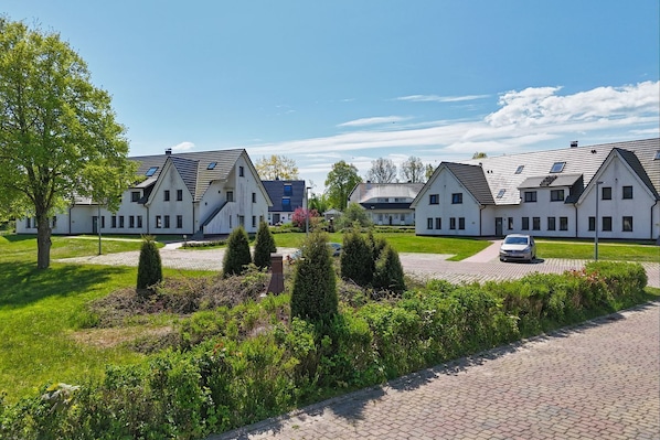 Une rangée de maisons modernes, de plain-pied, avec une allée pavée et des pelouses bien entretenues.