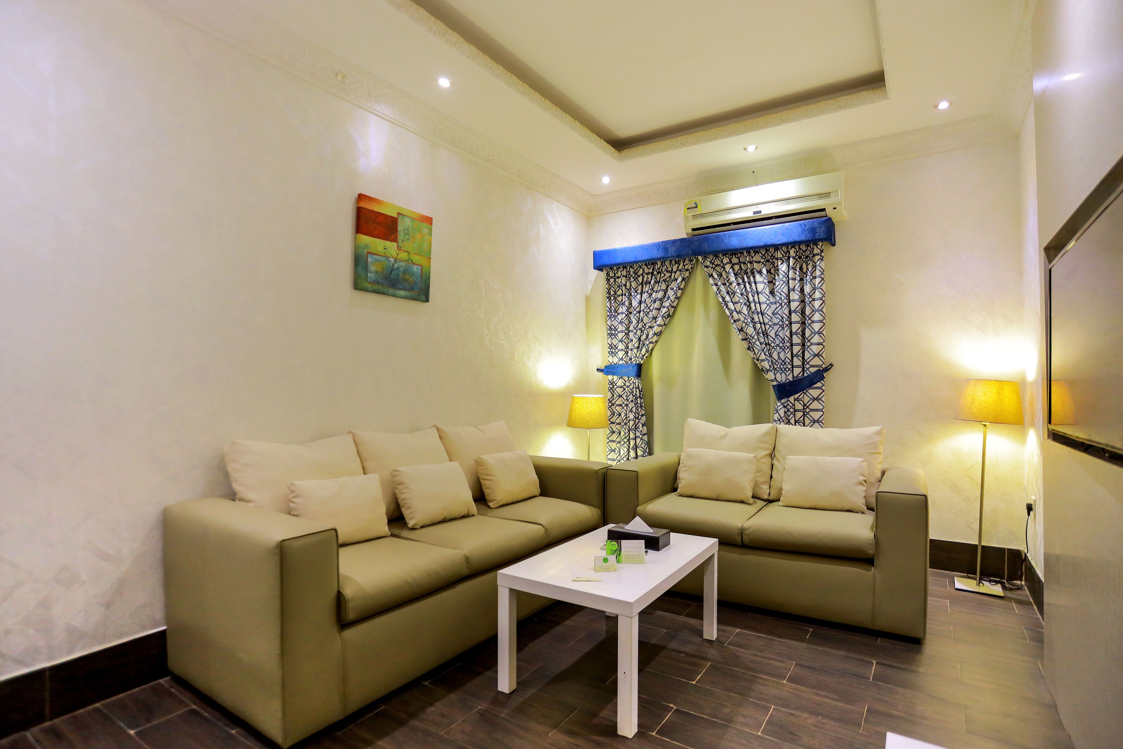 A living room with two beige sofas, a white coffee table, and patterned curtains.