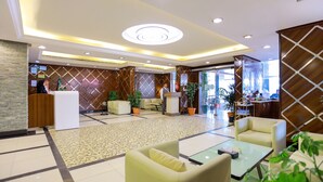 A hotel lobby with a reception desk, seating area, and a large window.