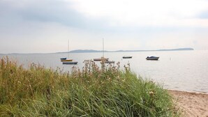 A calm lake with several boats anchored in the water, surrounded by grassy areas and distant landforms. - Haus Sonnenblume - idyllic location, vacation apartment with terrace, sea view - House (Putbus)