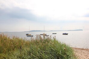 A calm lake with several boats anchored in the water, surrounded by grassy areas and distant landforms. - Haus Sonnenblume - idyllic location, vacation apartment with terrace, sea view - House (Putbus)
