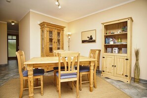 A dining area with a wooden table and chairs, a cabinet with glass doors, and a framed picture on the wall.