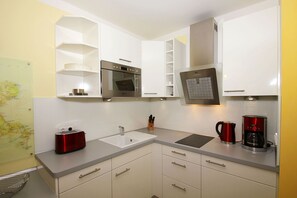 A modern kitchen with white cabinetry, a stainless steel oven, a coffee maker, and a toaster.