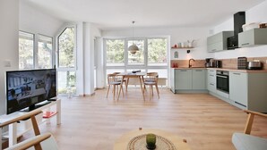 A modern kitchen with a dining area, large windows, and a flat-screen TV. - Gorch-Fock-Str 16 Apartment 6 - Gorch-Fock-Str 16 (Timmendorfer Strand)