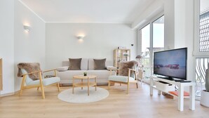A modern living room with a sofa, two armchairs, a coffee table, a TV, and a bookshelf. - Gorch-Fock-Str 16 Apartment 6 - Gorch-Fock-Str 16 (Timmendorfer Strand)