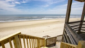Une terrasse en bois qui mène à une plage et offre une vue dégagée sur l’océan.