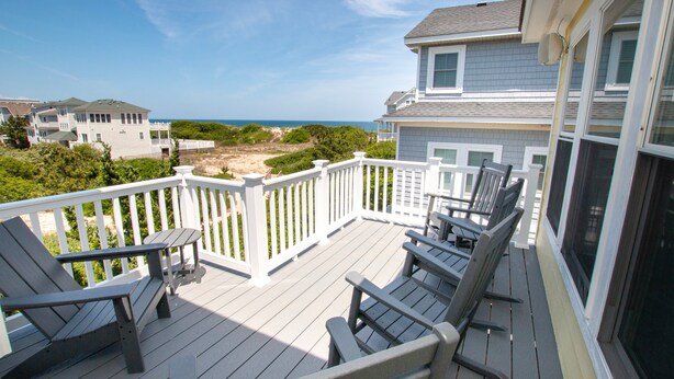A wooden deck with outdoor furniture, a white railing, and a view of the ocean and beach. - Oceanside, 8 BRs, Private Pool, Theater Room, Rec Rm, Hot Tub, OL126, Knot Tide Up (Corolla)