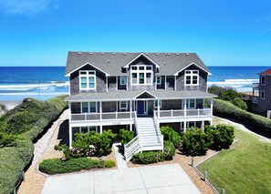 A two-story house with a front porch, a staircase, and a view of the ocean. - OCEANFRONT, 10 BRS, ELEV, Pool, Rec Rm, Theater Rm, OH1251, Beach Plaza (Corolla)