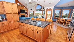 A kitchen with wooden cabinets, a granite countertop, and a built-in oven. - Semi-Oceanfront, Close to Beach Access, Private Pool, Hot Tub, 109, Happy Ours (Corolla)