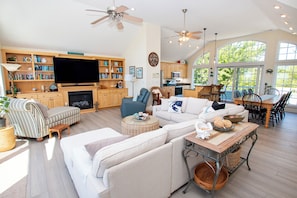 A spacious living area with a fireplace, a television, and a dining area with a view of the outdoors.