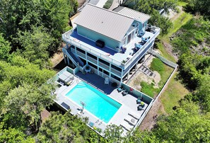 A multi-story building with a rooftop pool, outdoor seating, and a large deck area.