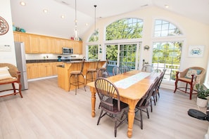 A spacious kitchen with wooden cabinets, a central island, and a dining area with a large table and chairs.