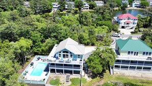A large house with a swimming pool, surrounded by dense trees and a lake. - Soundfront, ELEV, Private Pool, Pool Table, Water Views, VOH1, Soundly Sea-Cluded (Corolla)