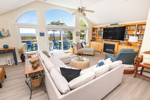 A spacious living room with a large sofa, a television, and a bookshelf.