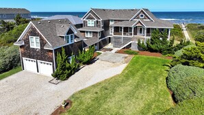 Een groot, twee verdiepingen tellend huis met een overdekte veranda en uitzicht op zee.