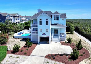 A two-story house with a front porch, a swimming pool, and a well-maintained lawn.