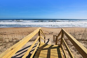 A wooden boardwalk leading to a beach with waves in the background.