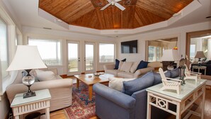 A spacious living room with a high ceiling, large windows, and a view of the outdoors. - OCEANFRONT, SUN-SUN, Pool, ELEV, Ocean Vws, PM100, Ships In (Duck)