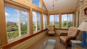 A sunroom with large windows offering a view of a coastal landscape. - OCEANFRONT, SUN-SUN, Pool, ELEV, Ocean Vws, PM100, Ships In (Duck)