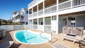 A pool area with lounge chairs and a building with multiple balconies. - Oceanside, Private Pool, Hot Tub, Close to Beach Access, OL656, Bali Dreams (Corolla)