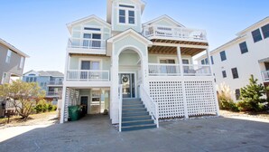 A multi-story residential building with a central entrance, a covered porch, and a staircase leading to the upper floor. - Oceanside, Private Pool, Hot Tub, Close to Beach Access, OL656, Bali Dreams (Corolla)