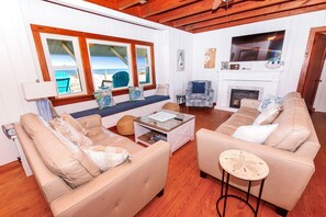 A living room with two sofas, a coffee table, and a fireplace. There are windows with views of the beach. - OCEANFRONT, Ocean views, Dogs Welcome! KH10, Beach House (Kitty Hawk)