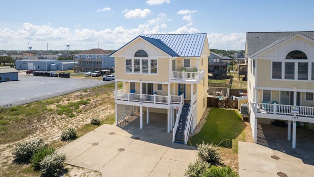 A beachfront property with two-story buildings, a parking lot, and a grassy area. - Semi-Oceanfront, Private Pool, Hot Tub, Game Room, KD1502, Tide Watcher (Kill Devil Hills)