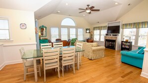 A spacious living room with a dining area, a fireplace, and a television. - Semi-Oceanfront, Private Pool, Hot Tub, Game Room, KD1502, Tide Watcher (Kill Devil Hills)