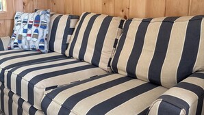 A striped sofa with a framed sign above it that reads "EAST COAST". -  Steps to private Beach, Golf Course, AC, tandem Kayak for Guests (South Yarmouth)