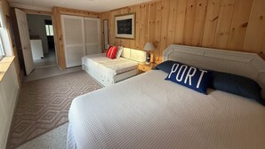 A bedroom with a bed, a nightstand, a lamp, a wardrobe, and a door leading to another room. -  Steps to private Beach, Golf Course, AC, tandem Kayak for Guests (South Yarmouth)