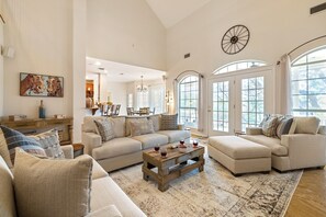 Relax in this stylish living room with a sofa, ottoman, and coffee table, surrounded by a beautiful painting and elegant chandelier.