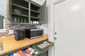 A kitchen with a microwave, coffee maker, and a cabinet with glassware. - Leander 3BR Retreat | Lake Travis Access (Leander)