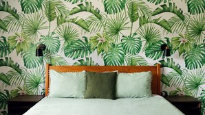 A bed with a wooden headboard, two bedside tables, and a wall with a tropical leaf pattern. - Leander 3BR Retreat | Lake Travis Access (Leander)
