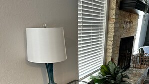 A modern interior with a glass table, a lamp, a potted plant, and a fireplace. - Leander 3BR Retreat | Lake Travis Access (Leander)