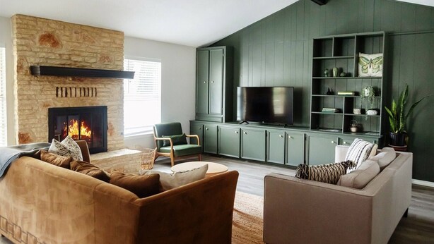 A living room with a stone fireplace, a television, green cabinets, and a sofa. - Leander 3BR Retreat | Lake Travis Access (Leander)