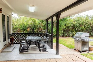 An outdoor patio with a table and chairs, a grill, and a view of a garden. - Leander 3BR Retreat | Lake Travis Access (Leander)