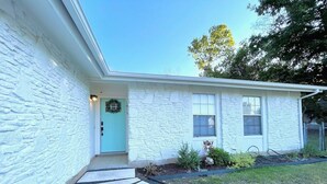 A house with a stone facade, a blue door, and a garden with a stone pathway. - Leander 3BR Retreat | Lake Travis Access (Leander)
