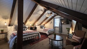 Une chambre mansardée chaleureuse avec un plafond en pente, deux lits, une petite table et une chaise.