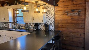 Une cuisine moderne avec des meubles en bois, un plan de travail noir et une pancarte indiquant « BIENVENUE ».